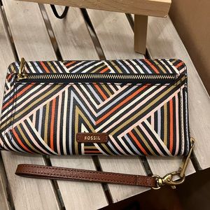 A beautiful colorful fossil wallet with brown leather slides for credit cards.